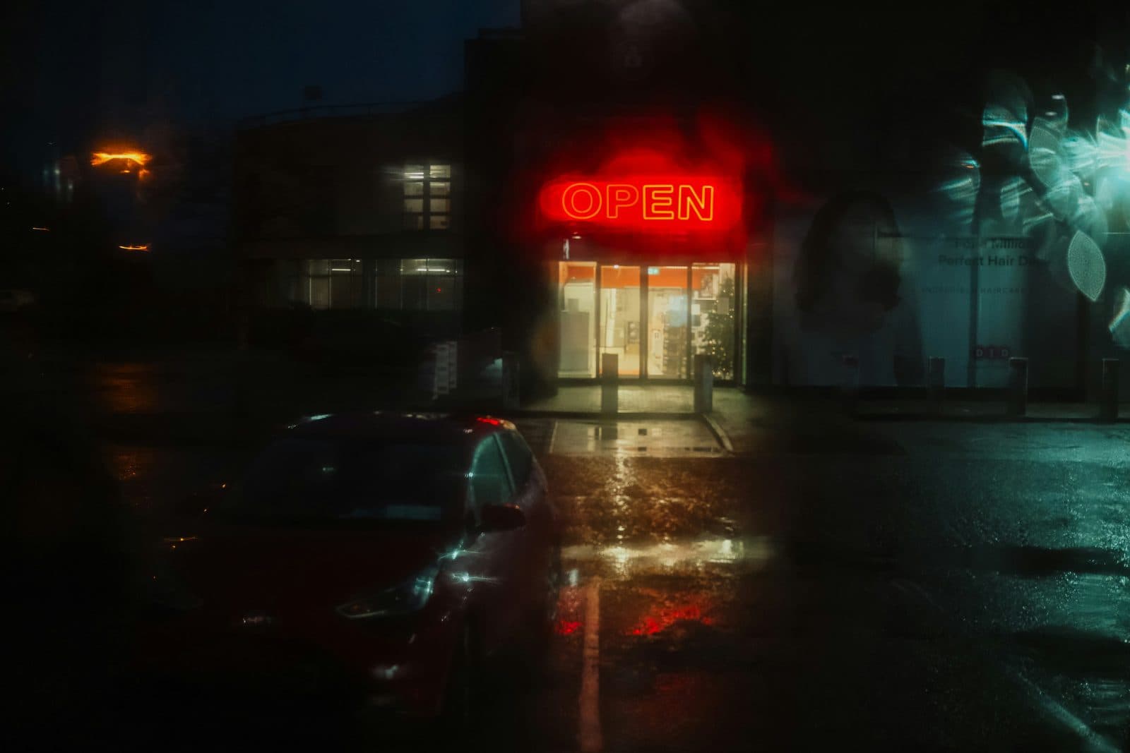 A late night storefront lit up in the rain